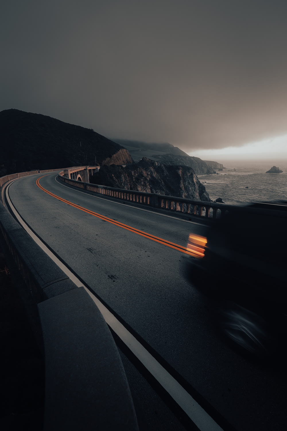 a car driving down a road next to the ocean