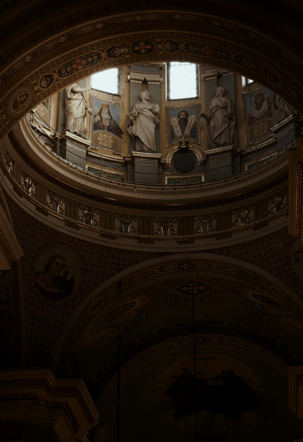 the ceiling of a large building with statues on it