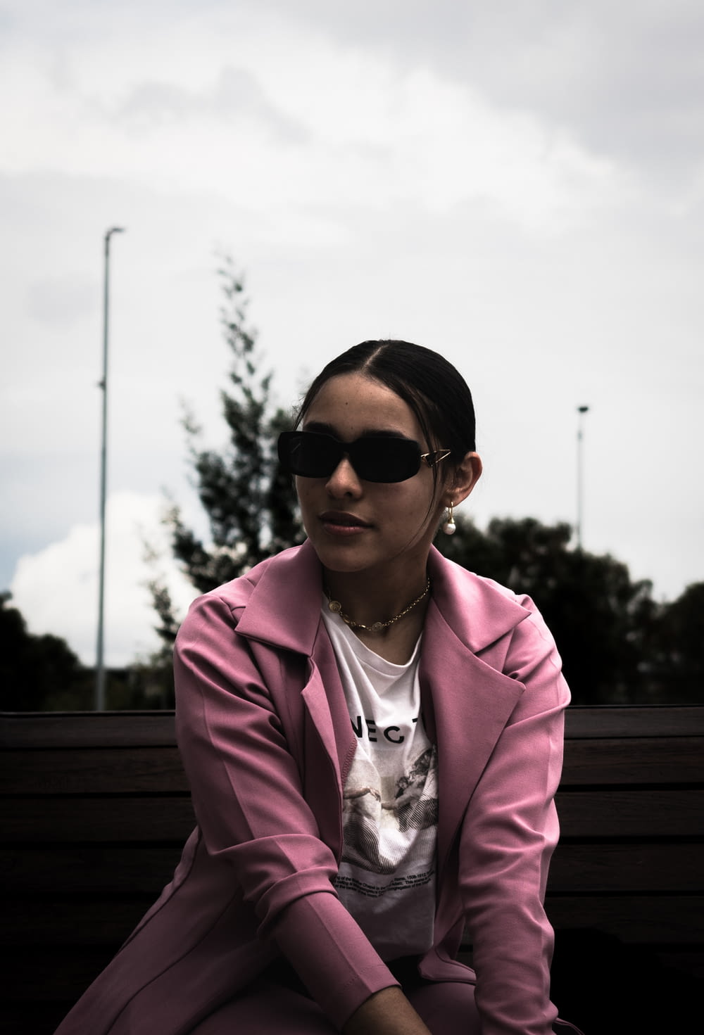 a woman wearing sunglasses sitting on a bench