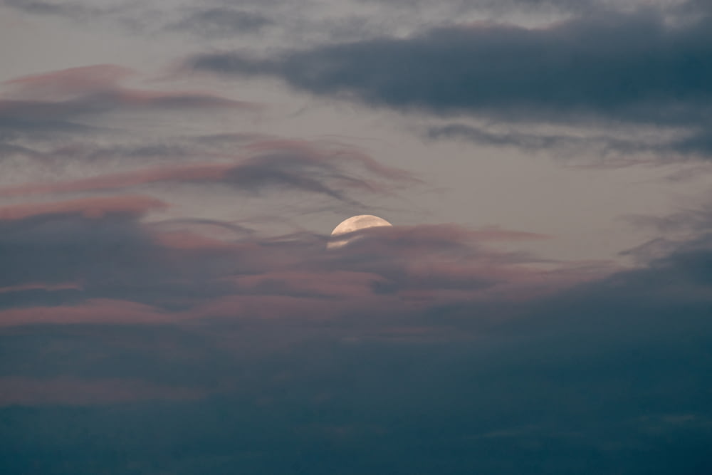 a full moon is seen through a cloudy sky