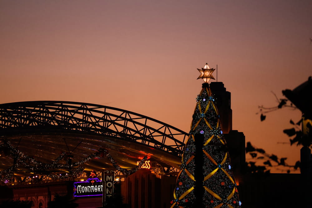 a lit up christmas tree in front of a bridge