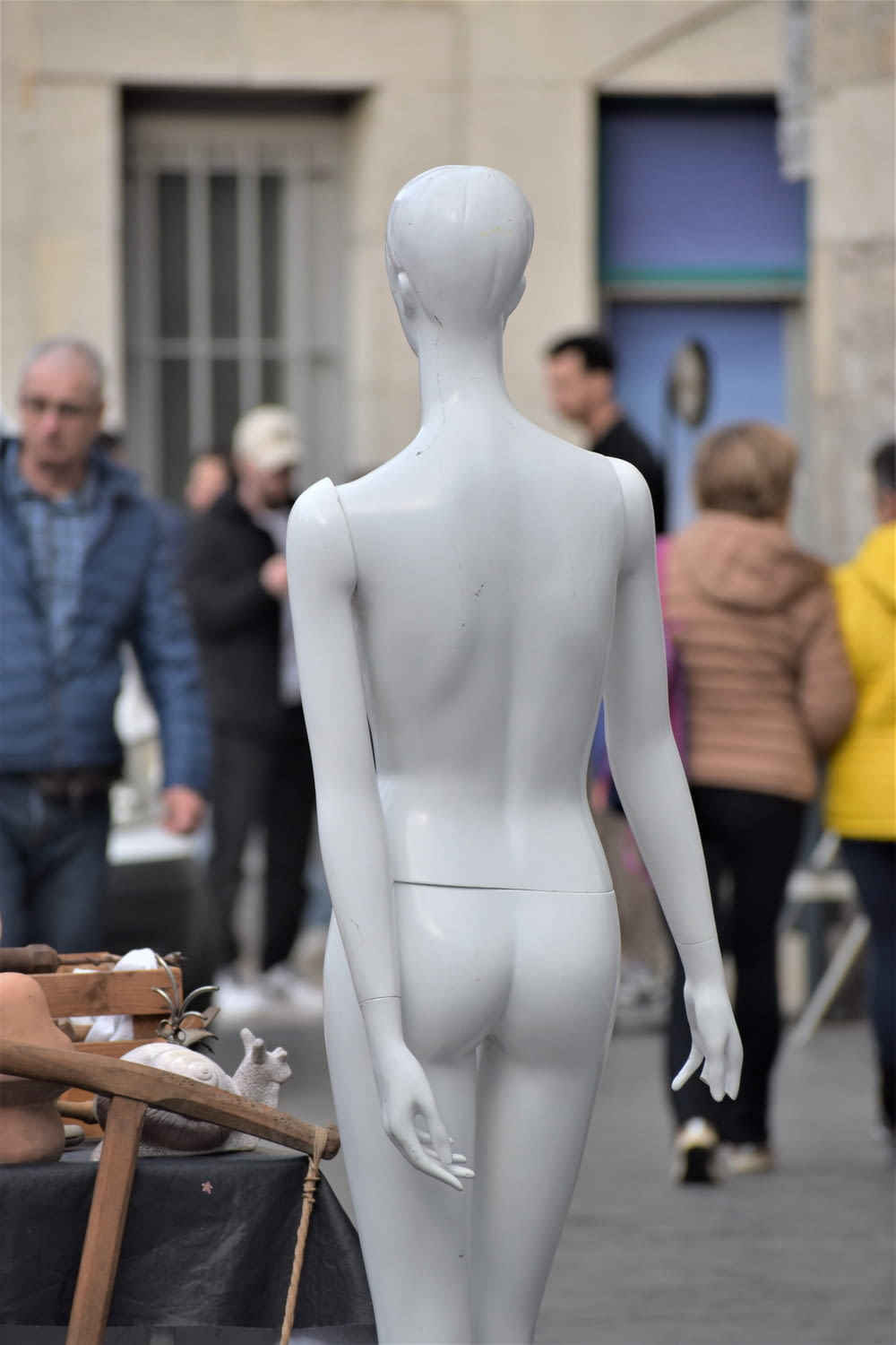 a white mannequin standing in front of a crowd of people