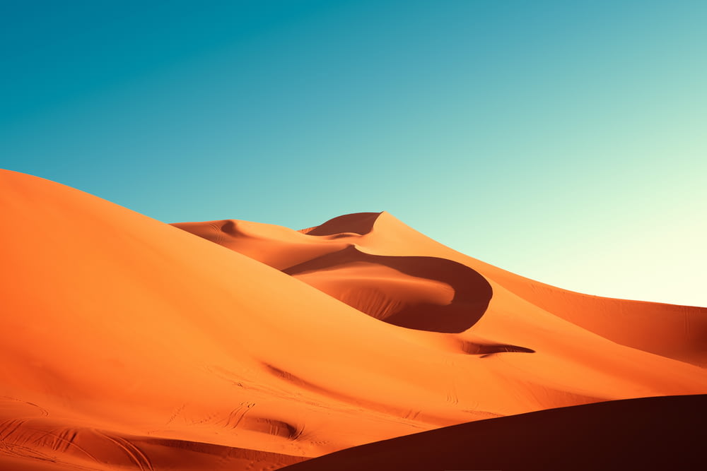 a group of sand dunes with a blue sky in the background