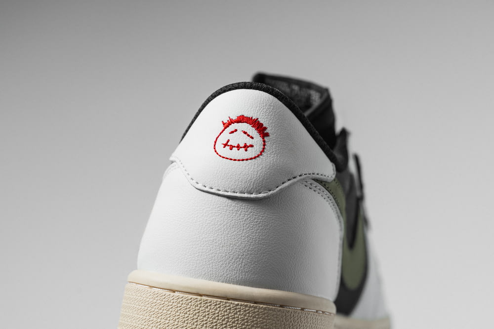 a white and black sneaker with a red smiley face on the side