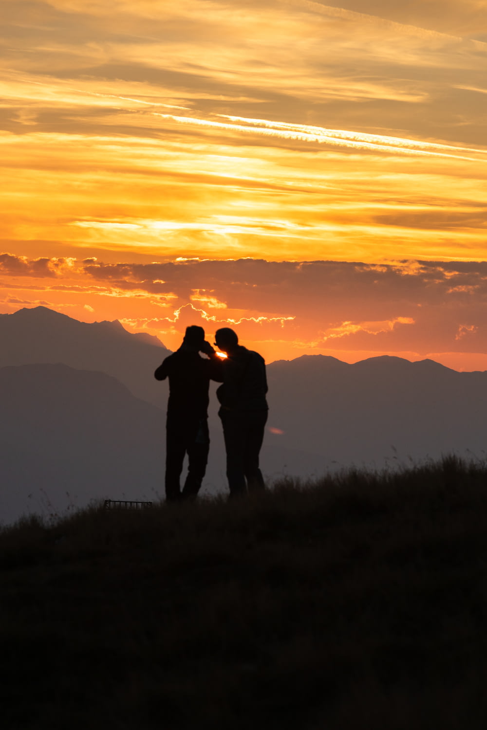 um casal de pessoas em pé no topo de uma colina coberta de grama
