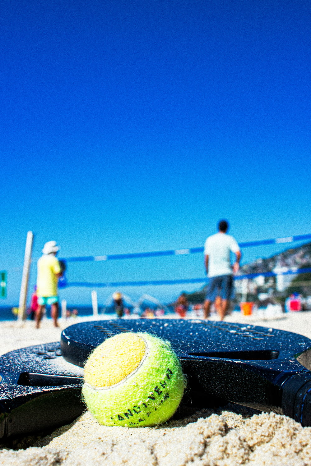 a tennis ball and racket laying on the sand