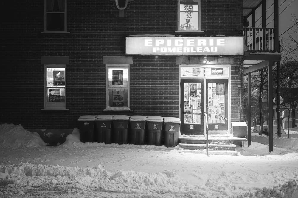 a black and white photo of a store in the snow