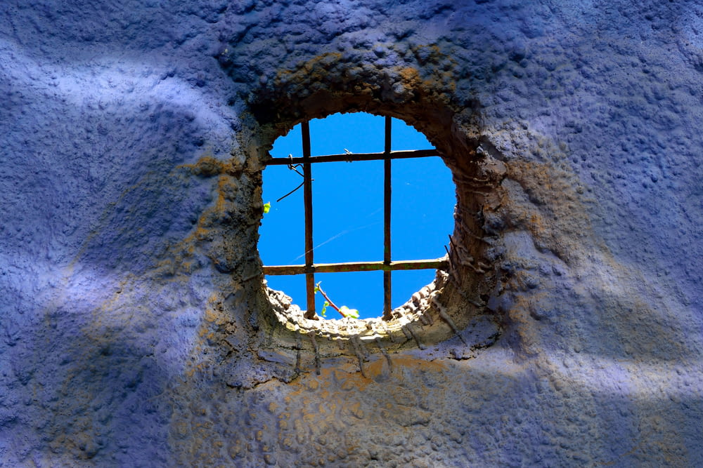 a hole in a cement wall with a blue sky in the background