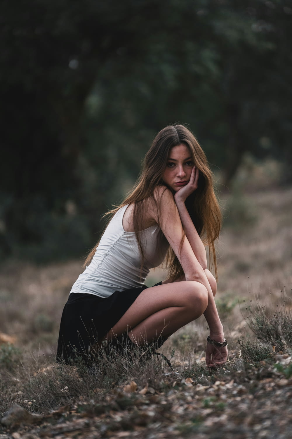 a beautiful young woman kneeling down in a field