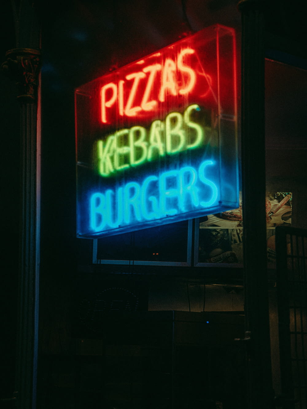 a neon sign that says pizzas, kebabs, burgers