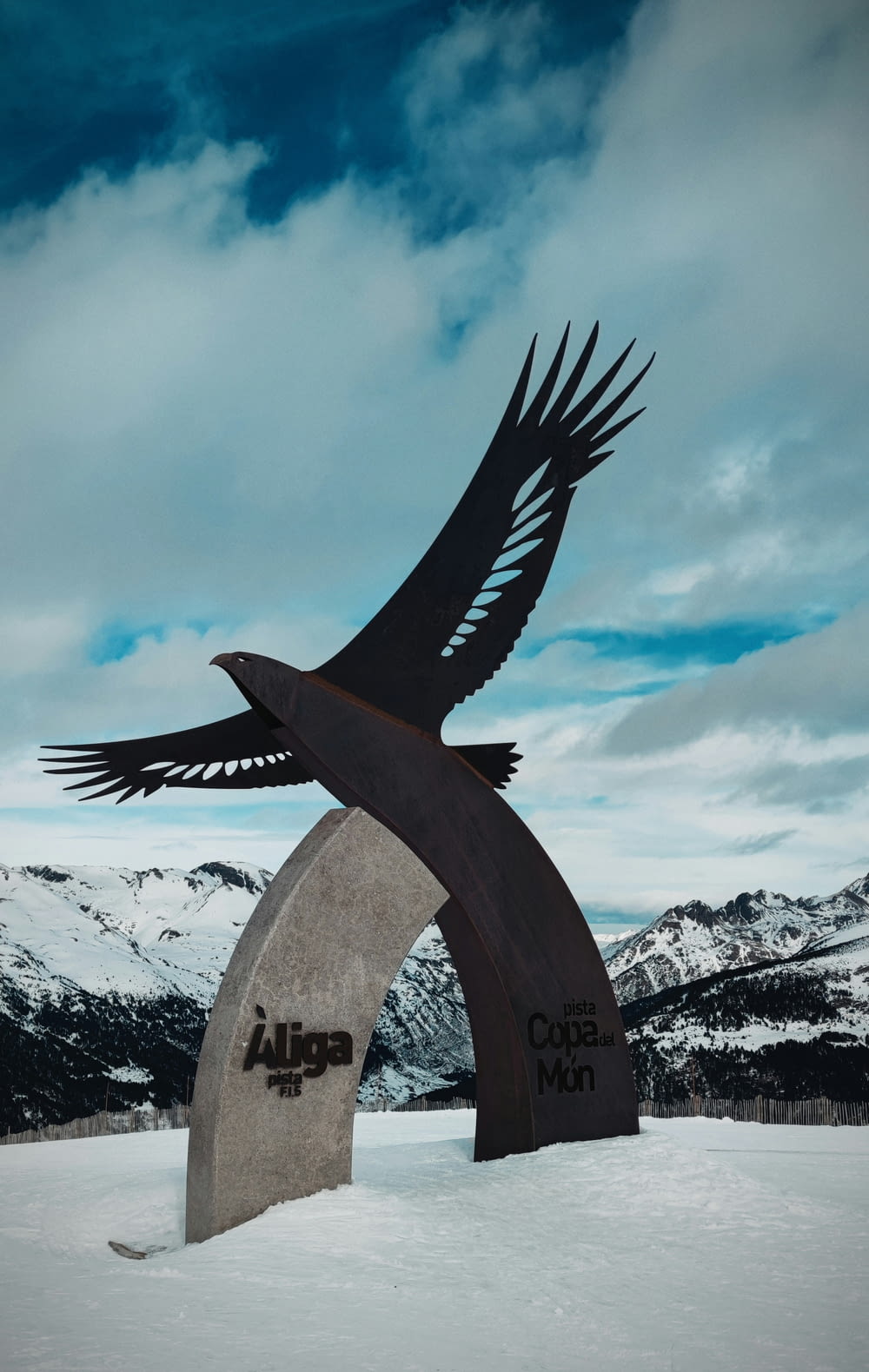 a sculpture of a bird flying over a snow covered mountain