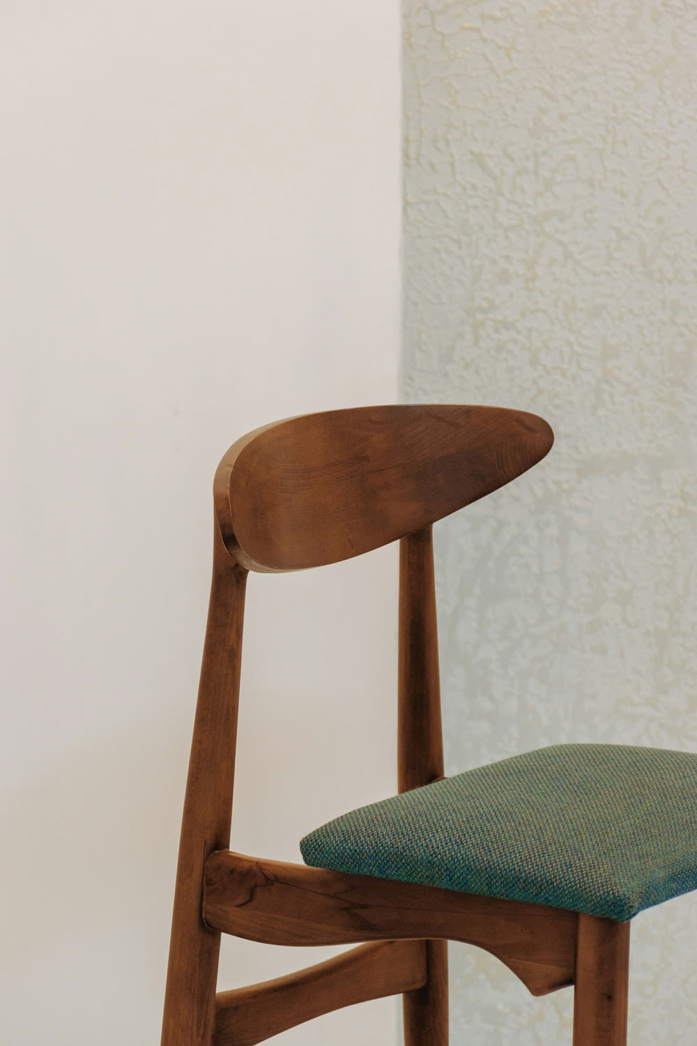 a wooden chair with a green seat cushion