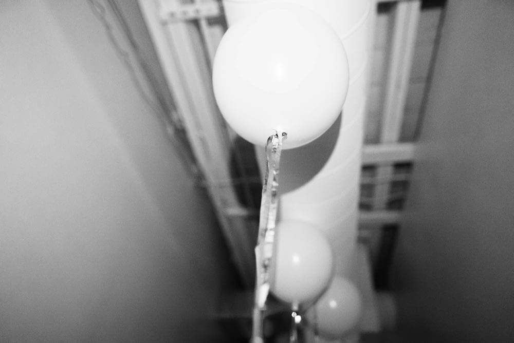 a black and white photo of balloons hanging from a ceiling