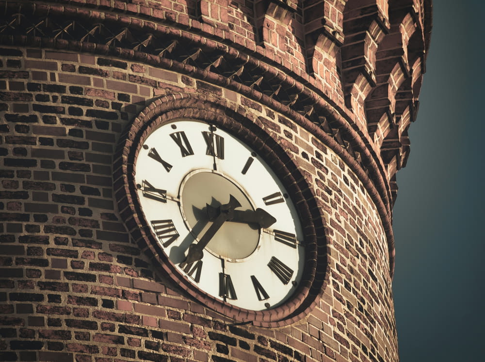 a clock on a brick tower with roman numerals