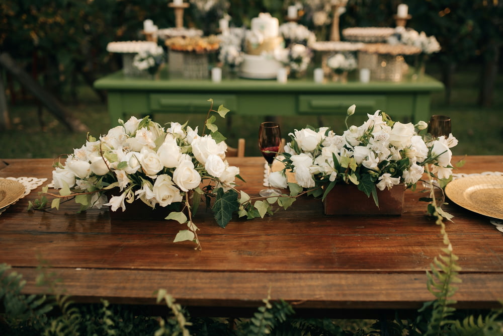 a wooden table topped with vases filled with white flowers
