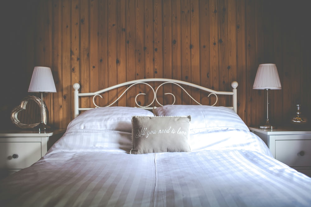 a bed with a white headboard and two lamps