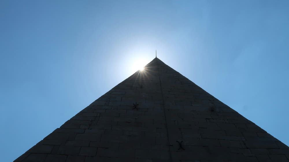 the sun shines brightly through the top of a pyramid