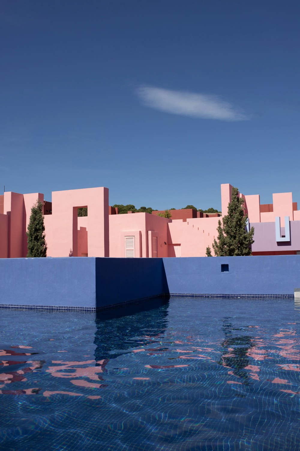 a blue pool with a pink building in the background