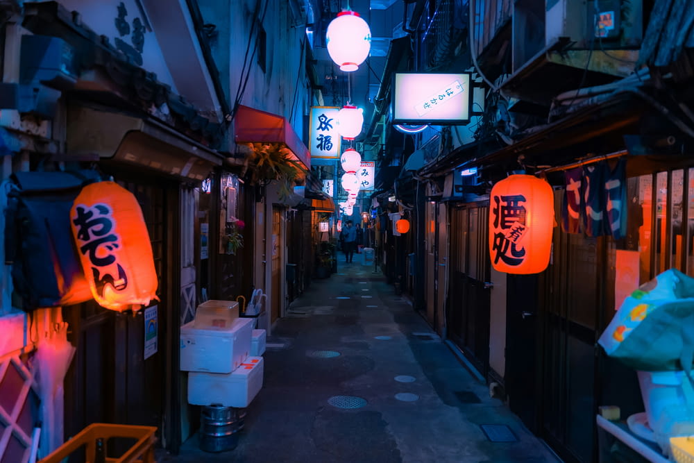 a narrow alley with lanterns hanging from the ceiling