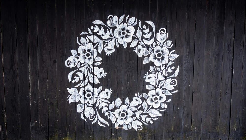 a painted white wreath on a black fence