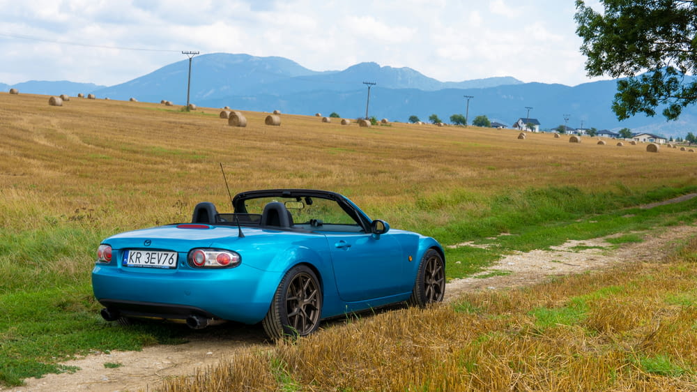 a blue sports car parked on a dirt road