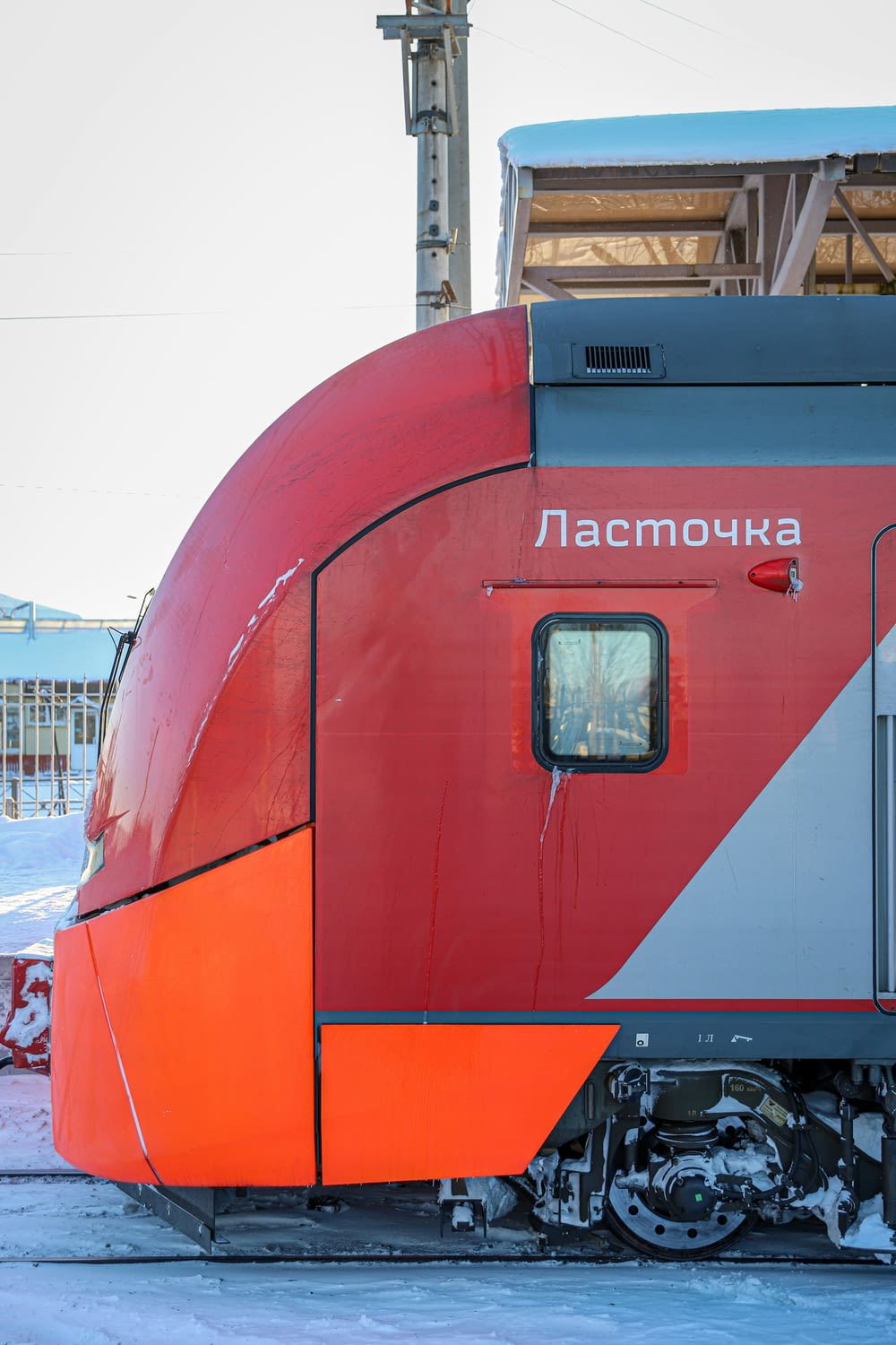 a red and grey train sitting on the tracks