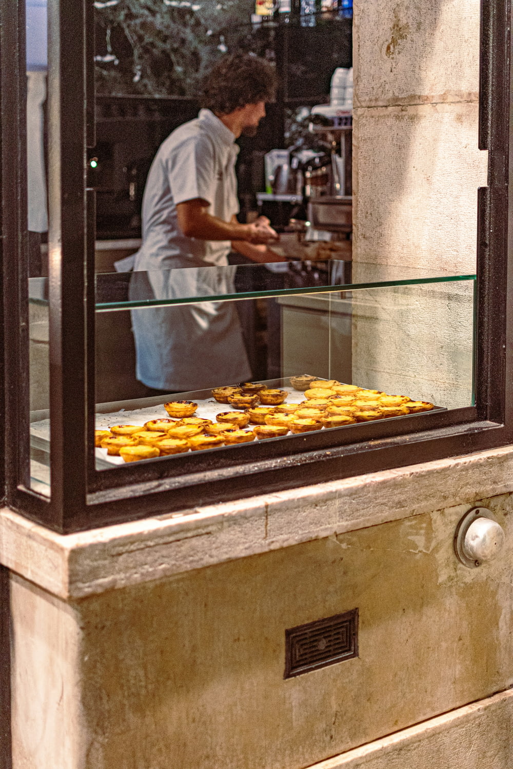 a man preparing food behind a glass counter