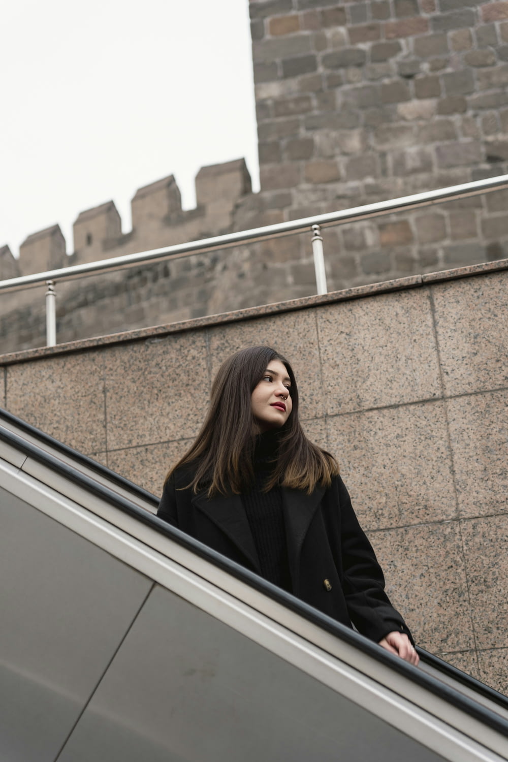 a woman standing on an escalator next to a building