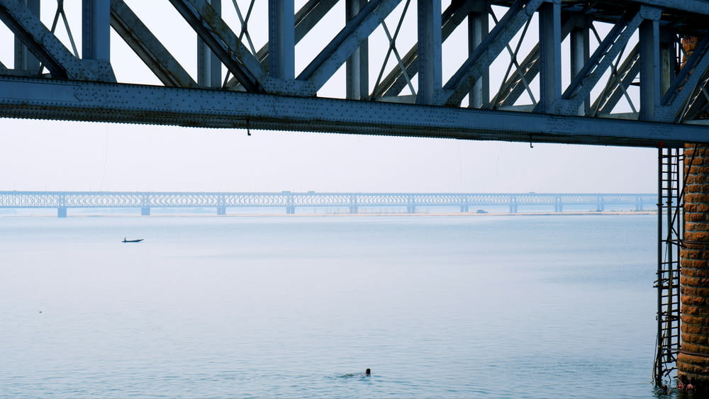 a person swimming in a body of water under a bridge