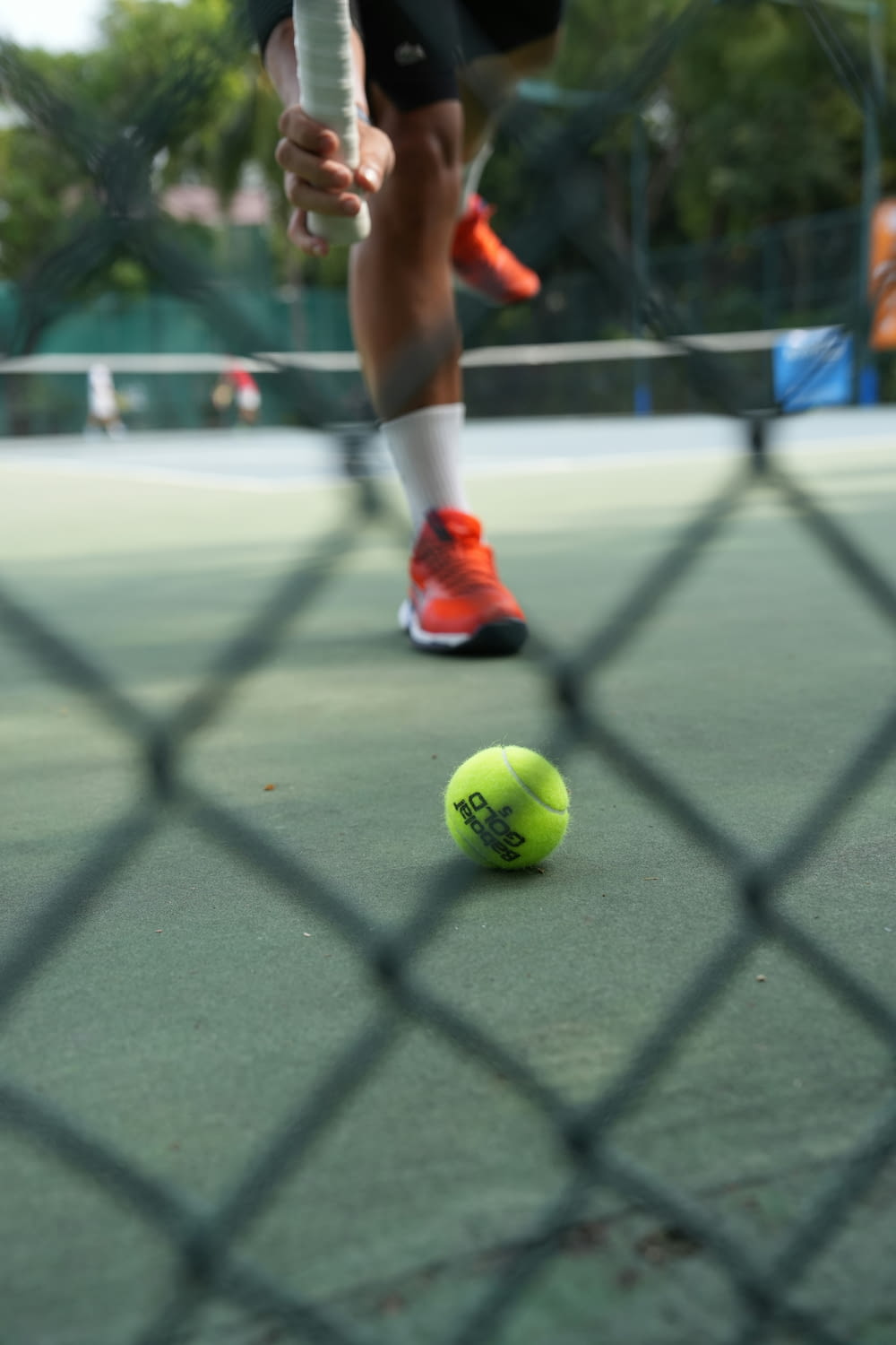 une balle de tennis sur un court avec une personne debout derrière elle