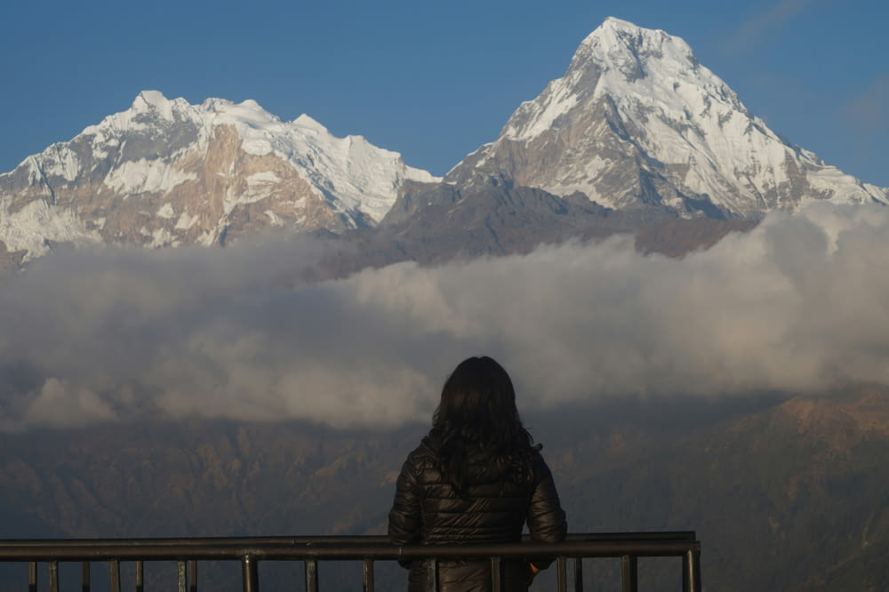a woman standing on a balcony looking at a mountain range