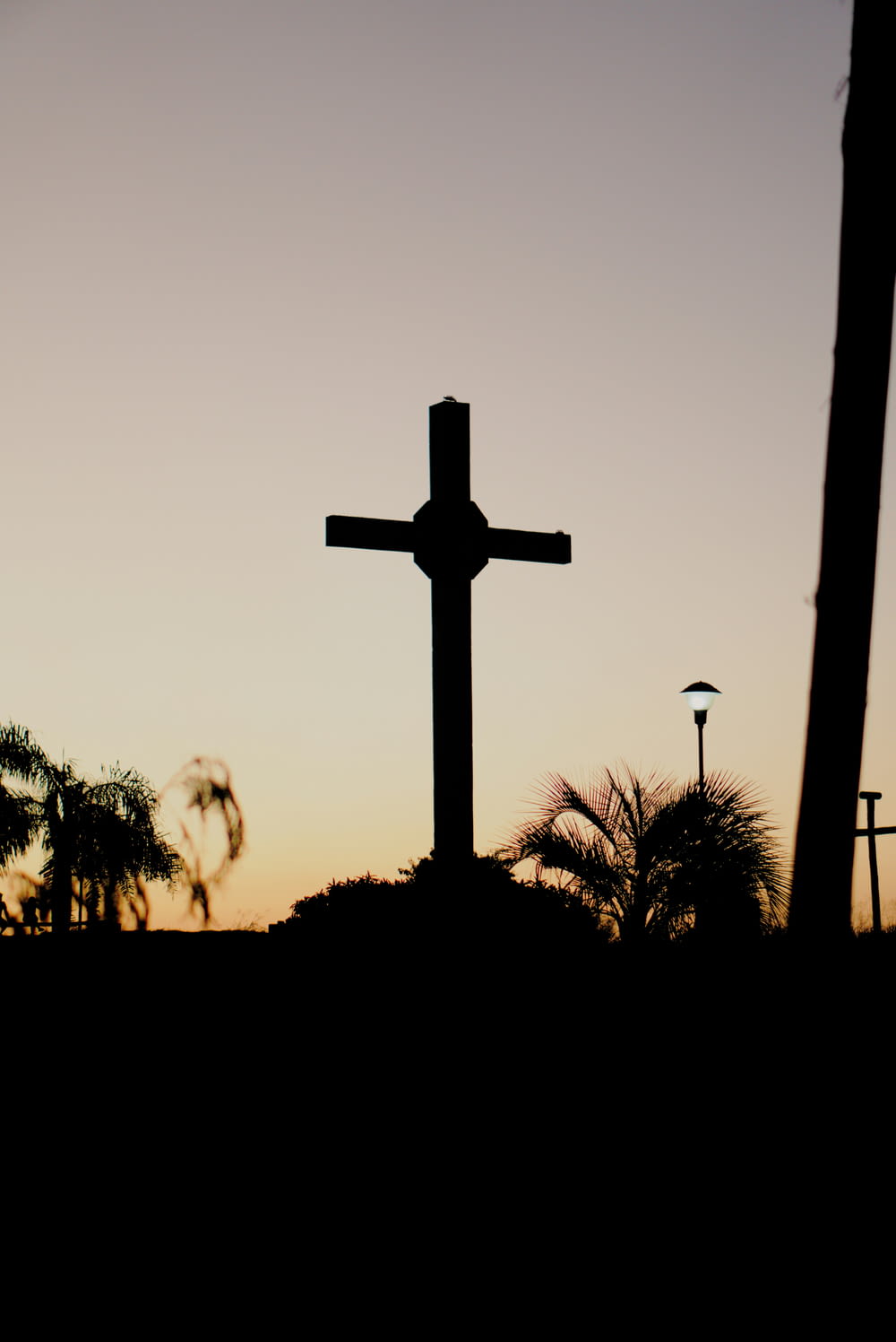 a cross is silhouetted against a sunset sky