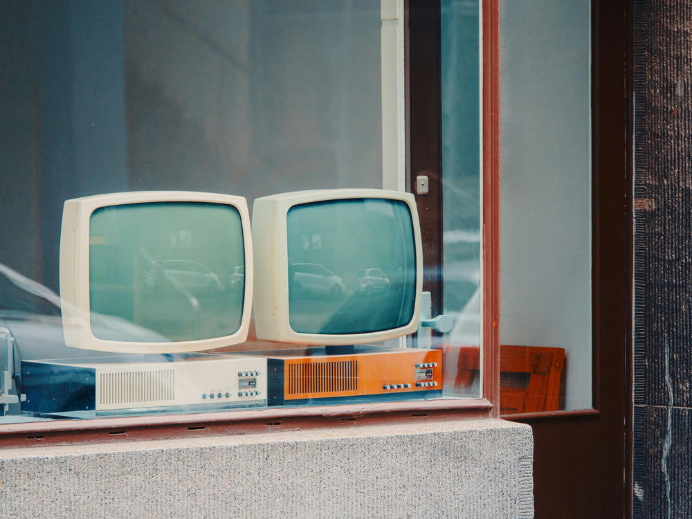 a couple of old tvs sitting in a window