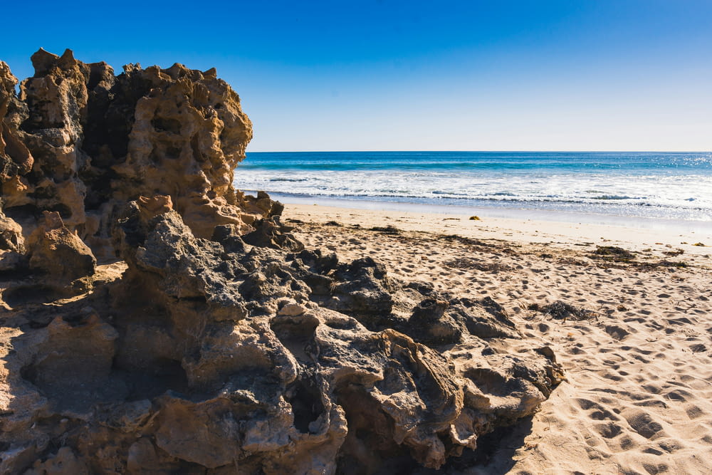 a rock formation on a sandy beach next to the ocean