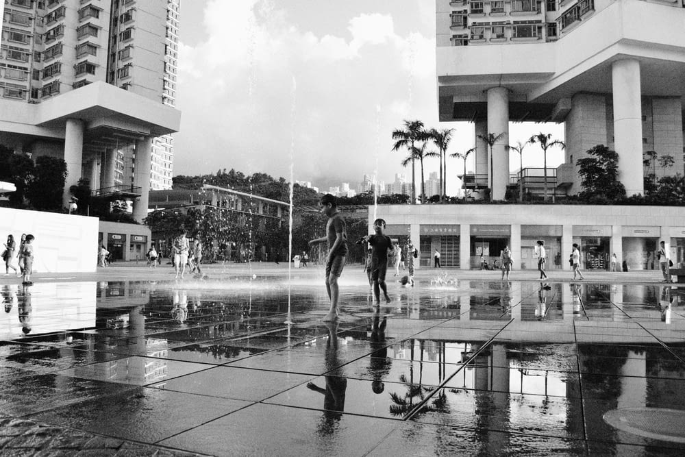 a black and white photo of people playing in a fountain