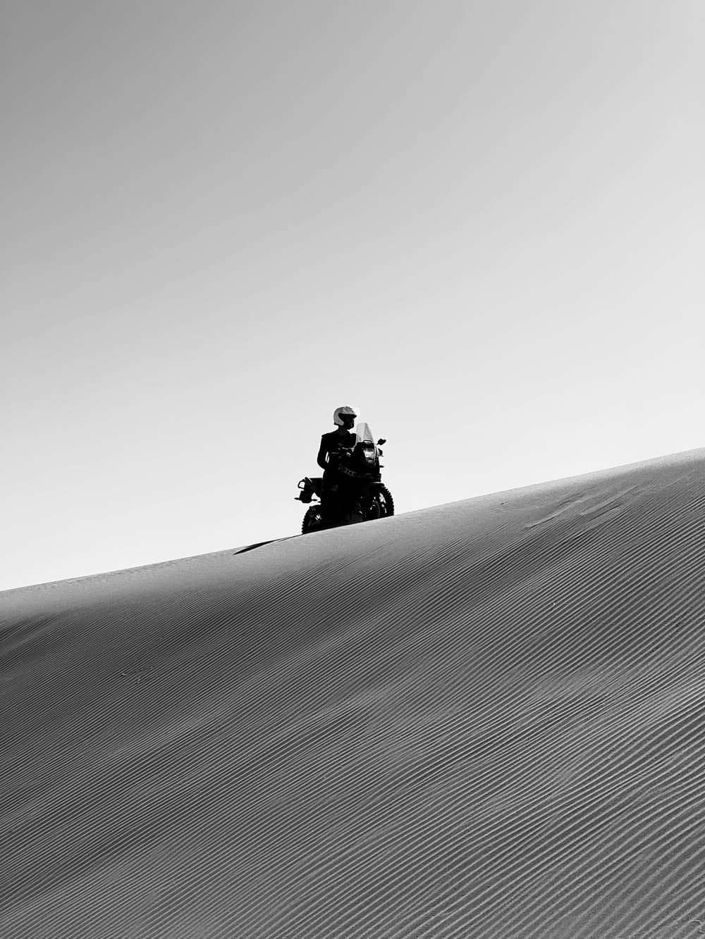 a man riding a motorcycle down a sand dune