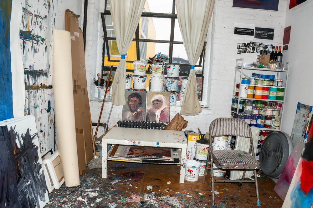 a messy room with a painting on the wall