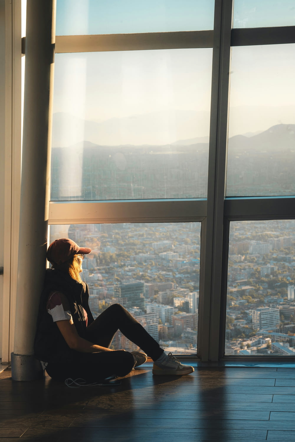 a person sitting on a ledge looking out a window