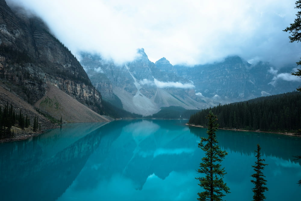 um lago azul cercado por montanhas sob um céu nublado