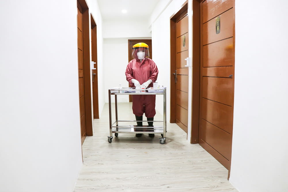 a man in a hard hat and overalls standing in a hallway