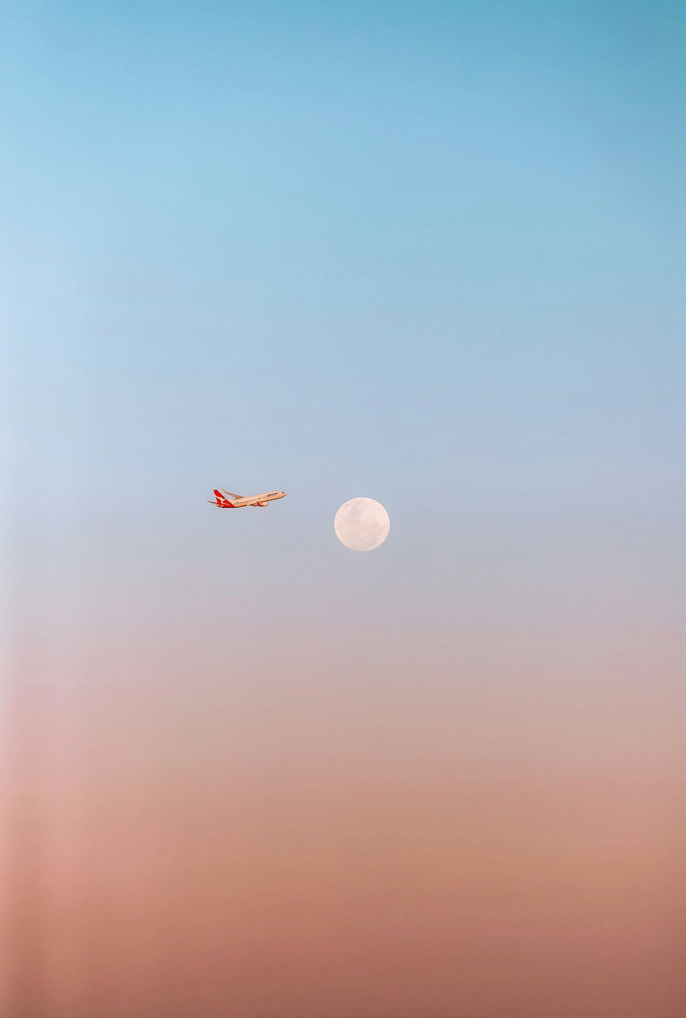 an airplane flying in the sky with a moon in the background