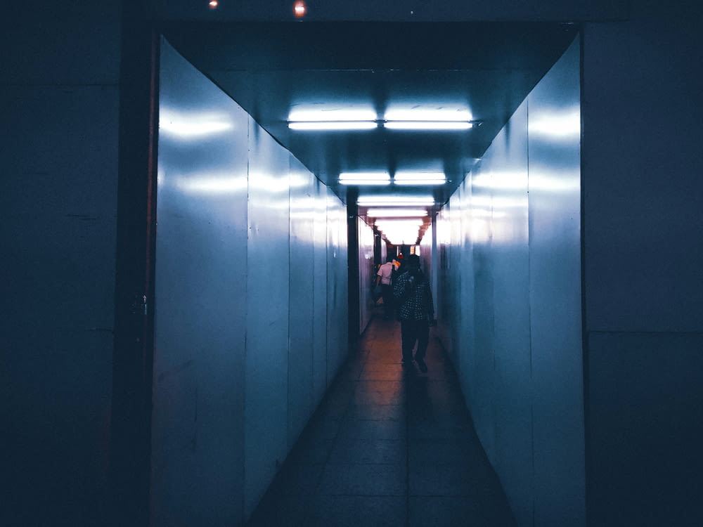 two people walking down a long hallway in the dark