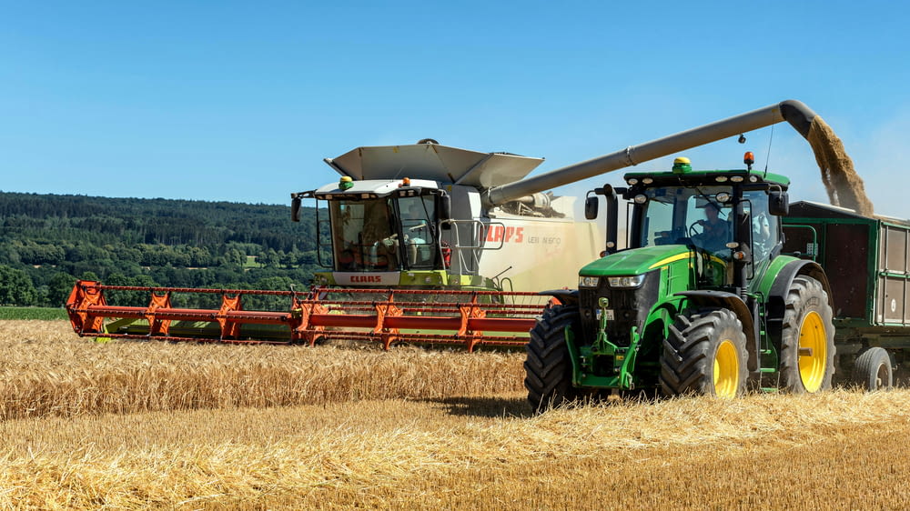 a tractor and a combine harvesting a field of wheat