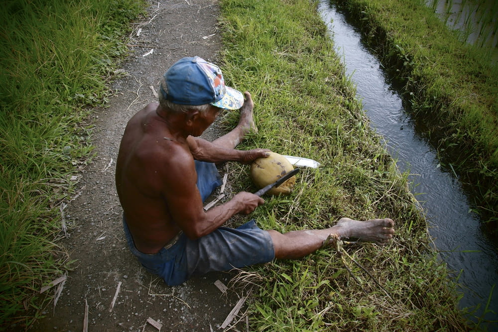 a man sitting on the side of a road next to a river