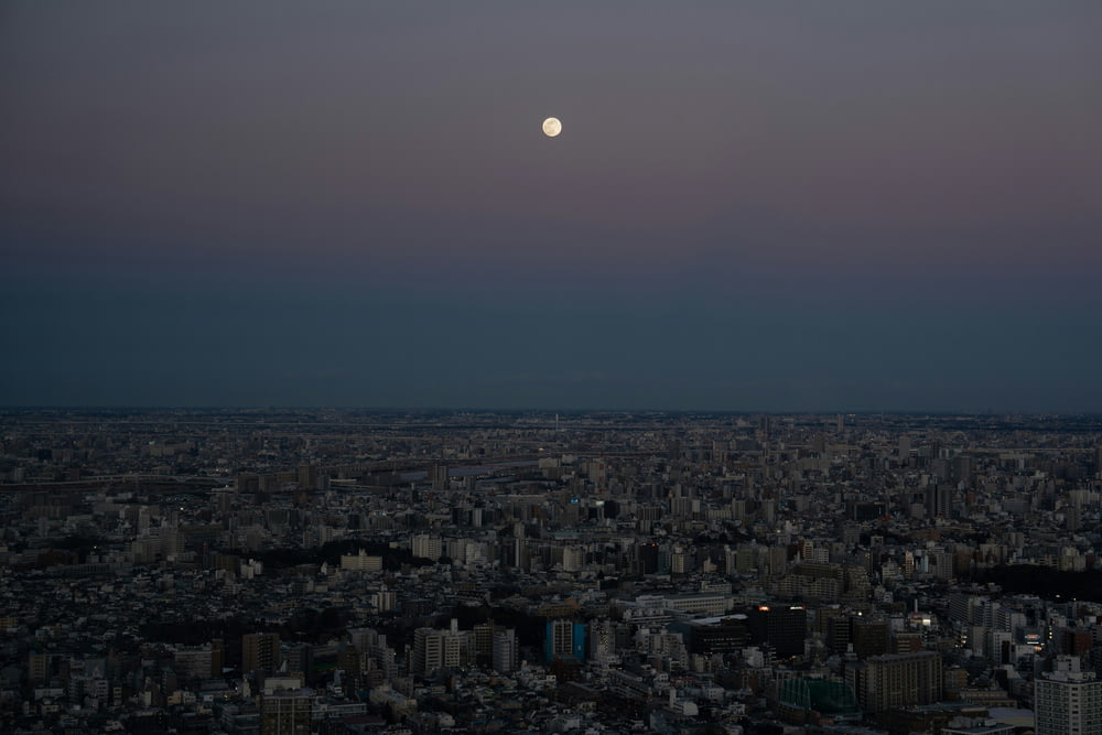a full moon over a city at night