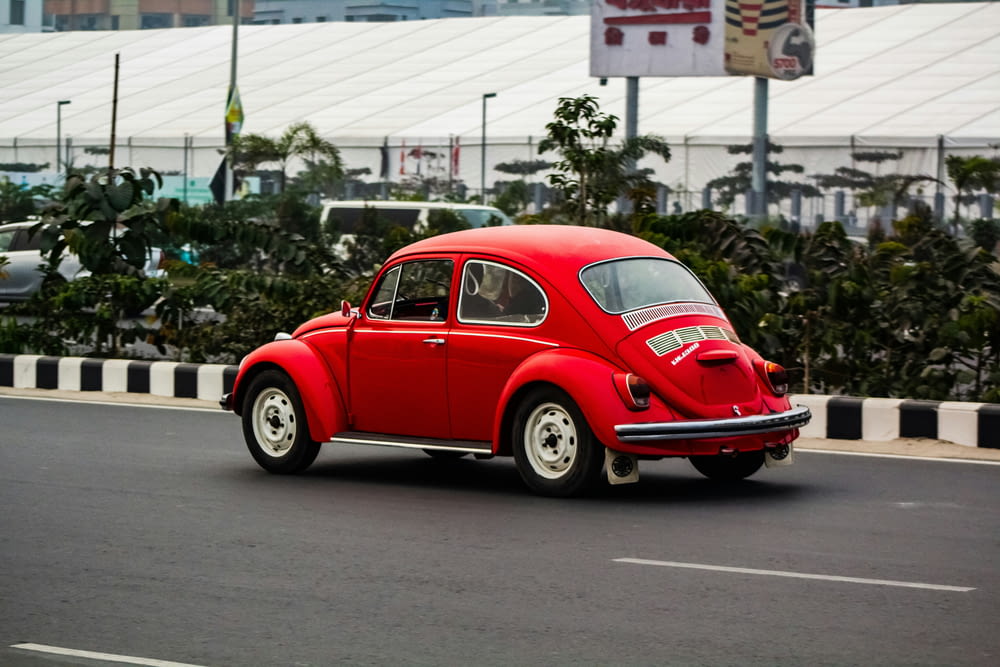 a red vw bug driving down a street