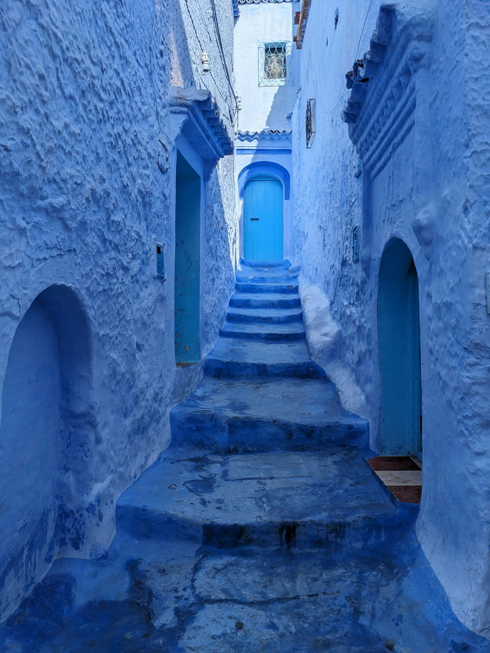 a narrow alleyway with blue painted walls and steps