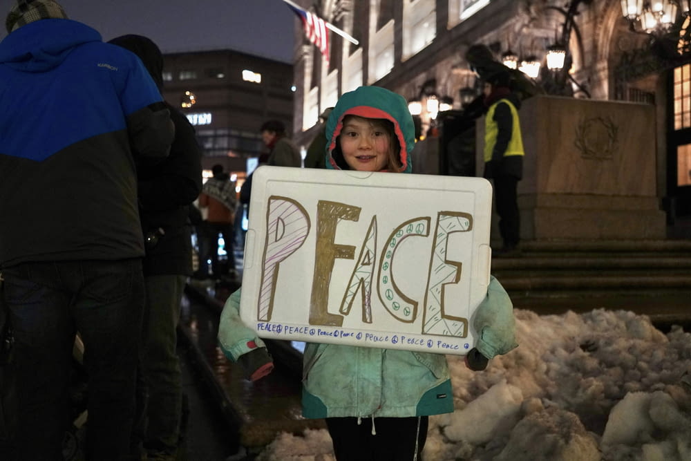 a little girl holding a sign that says peace