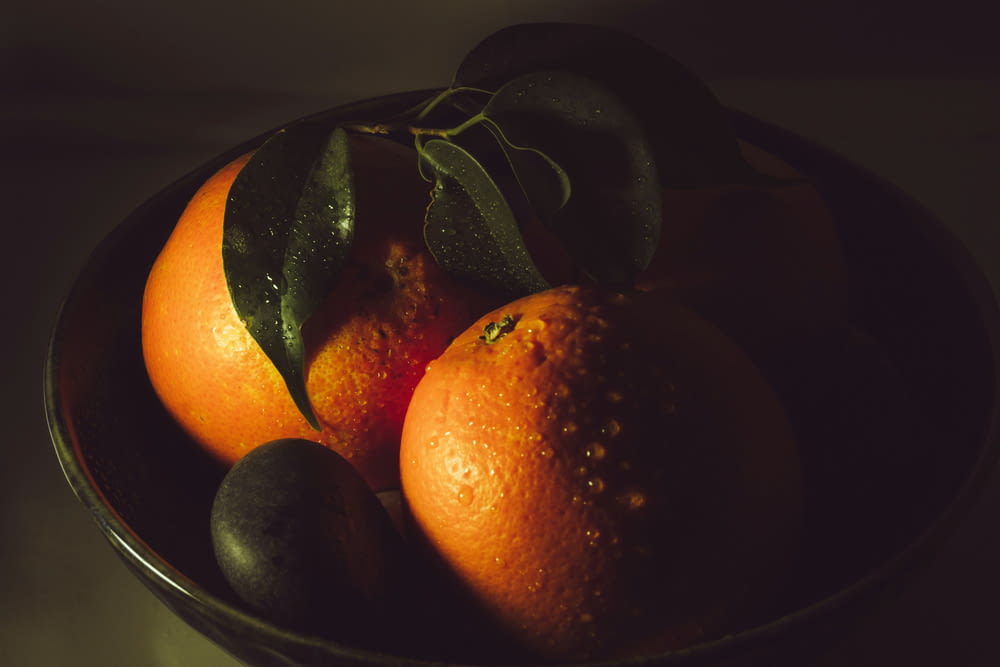 a bowl of oranges and avocados on a table