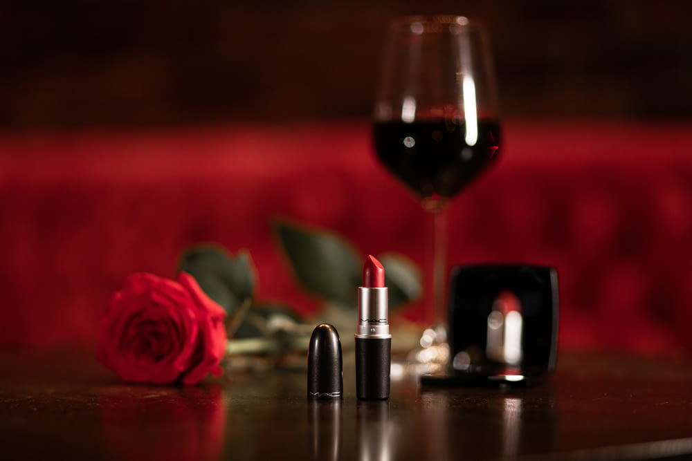 a glass of wine and a lipstick on a table